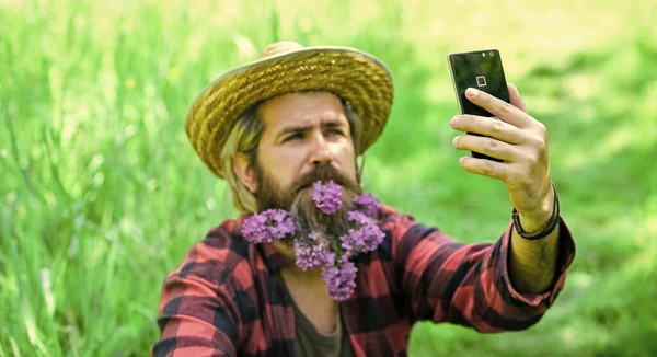 Homem do campo a fazer selfie ao telefone. proteger o ambiente verde. Agricultura agricultor descansar após o trabalho diurno. Trabalhador na quinta rural. agricultor com flor lilás na barba. Ecologia. Campo verde no verão — Fotografia de Stock