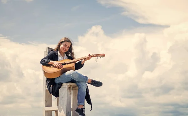 Μαθήματα μουσικής. μικρός κιθαρίστας στο φόντο του ουρανού. στυλ κάντρι. έγχορδο μουσικό όργανο. Παίξε ακουστική κιθάρα. Το κοριτσάκι παίζει κιθάρα και λατρεύει τη μουσική. αντίγραφο χώρου — Φωτογραφία Αρχείου