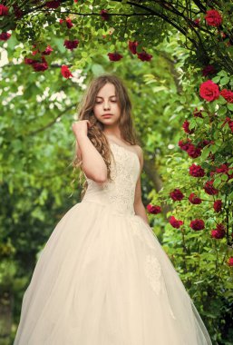 Romantik bir an. Şirin bayan. Mutlu çocukluk. Güzellik ve moda. Güzel çocuk gül kokusu alıyor. Bahar ve yaz doğası. Bahçedeki küçük kız. Çocuk parkta çiçek açmanın tadını çıkarıyor. Gelin için küçük melek
