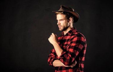 Cowboy life came to be highly romanticized. Man unshaven cowboy black background. Archetypal image of Americans abroad. Masculinity and brutality concept. Adopt cowboy mannerisms as a fashion pose clipart