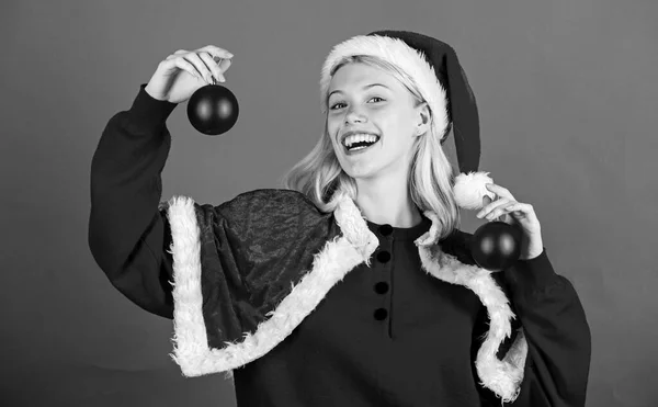 Conceito de preparação de Natal. Ano de Natal da época favorita. Diversão de Natal. Desfrute de celebração com traje e decoração. Menina feliz desgaste santa traje comemorar natal segurar bola decoração vermelho fundo — Fotografia de Stock