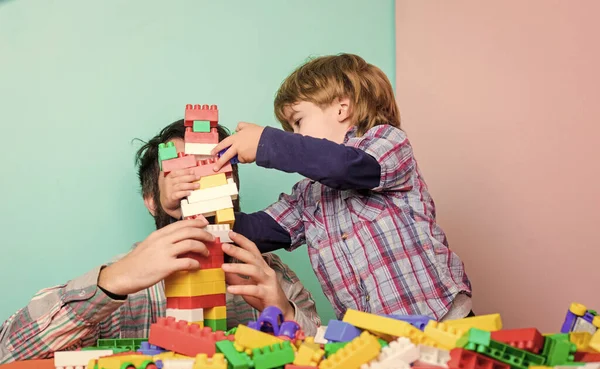 Çocuksu neşeli baba ve komik oğul. Babam çocuklarla oyuncak oynar. Baba ve çocuk plastik bloklar inşa ediyorlar. Mutlu bir aile. Çocuk gelişimi ve yetiştirme. Birlikte oynamanın önemi. Baba ve oğul eğlenin.