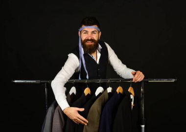 Siyah arka plandaki ceketlerin yanında neşeli yüzlü bir iş adamı..