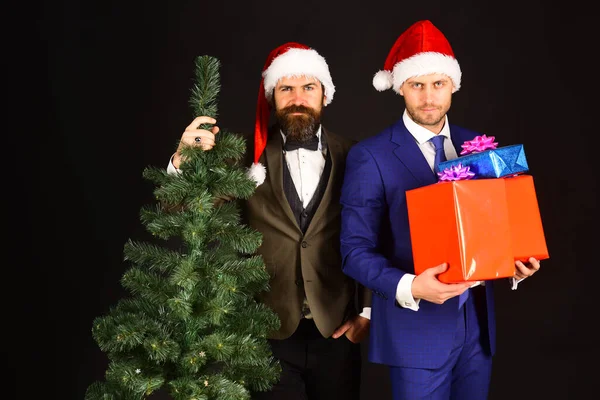 Muži v chytrých oblecích a Santa klobouky na hnědém pozadí — Stock fotografie