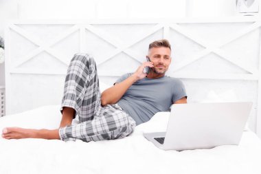 Uzaktan çalışma konsepti. Sosyal ağlar. Çevrimiçi dünya. İnternette sörf yapan adam. Çalışıyorum zaten. Dijital pazarlama. Uzaktan erişim. Hipster sakallı adam pijamalı serbest çalışan evde dinleniyor.