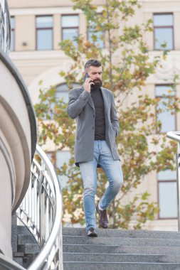 Hippi konuşması cep telefonundan merdivenlerden iniyor, şehir dışında, konuşuyor.