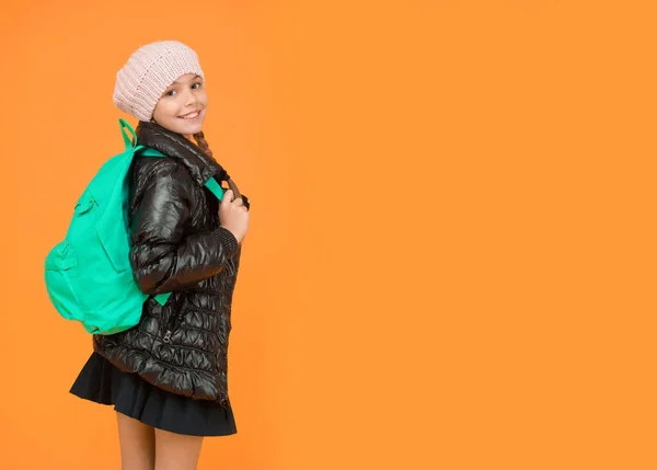 Een mode-outfit voor schoolmeisjes. Kind met rugzak. Modewinkel. Modeconcept. Meisje draagt gebreide muts en jasje met gele achtergrond. Schattige leerling. Herfst herfst winter. Koop kleding voor het schoolseizoen — Stockfoto