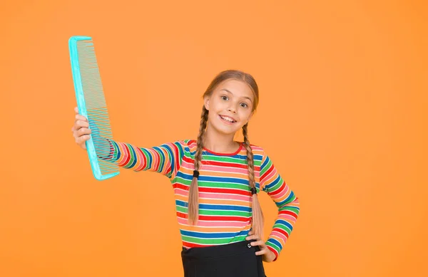 Kam niet alleen voor blond. Gelukkig kind houden blauwe kam gele achtergrond. Meisje glimlach met plastic haarkam. Kleine jongen kamt lang haar. Schoonheidssalon. Kappers. Kapsel — Stockfoto