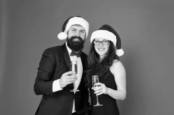 Feast of Christmas. tuxedo man with woman in santa hat. merry christmas and cheers everyone. business man and girl drink champagne. xmas party. formal couple in love celebrate new year