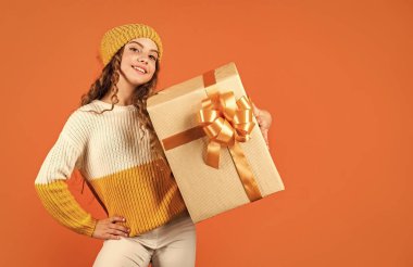 Doğum günü geleneği. Güzel makyaj yüzü kıvırcık saç stili. Çocuk hediye kutusunu tut. Alışveriş merkezi. Doğum günü kutlaması fikri. Modaya uygun küçük kız örgü şapka ve kazak giyiyor. Doğum günü sürprizi