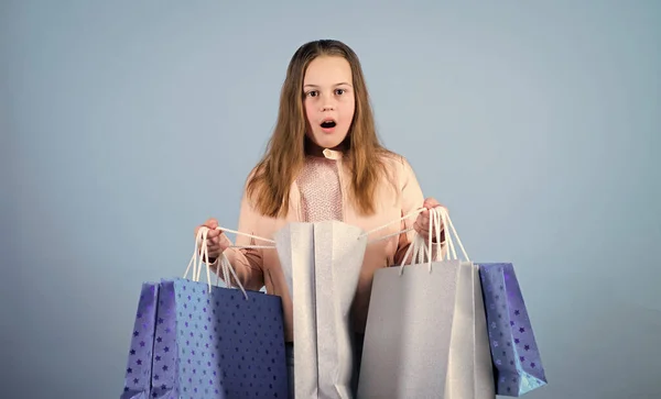 ¡Qué sorpresa! Ventas y descuentos. Niña pequeña con bolsas de compras. Ahorro de compra vacaciones. niño sorprendido. Niña con regalos. Moda infantil. asistente de tienda con paquete. Compras agradables —  Fotos de Stock