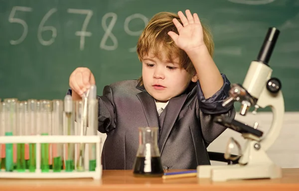 Technologie en wetenschapsconcept. Hij studeert biologie en scheikunde op school. Schoolonderwijs. Verken biologische moleculen. Peuter geniale baby. Jongen in de buurt van microscoop en reageerbuizen in de klas — Stockfoto