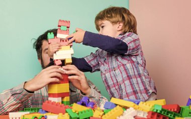 Baba ve oğul eğlenin. Çocuksu neşeli baba ve komik oğul. Babam çocuklarla oyuncak oynar. Baba ve çocuk plastik bloklar inşa ediyorlar. Mutlu bir aile. Çocuk gelişimi ve yetiştirme. Birlikte oynamanın önemi