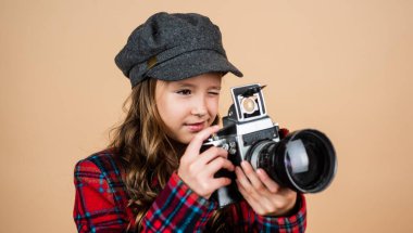 Paris 'li çocuk fotoğrafçısı retro kamera kullanıyor. Şık çocuk Fransız şapkası takıyor. Klasik dijital teknoloji. Kareli ceketli genç kız fotoğraf çekiyor. Mutlu çocukluk. fotoğrafçılık