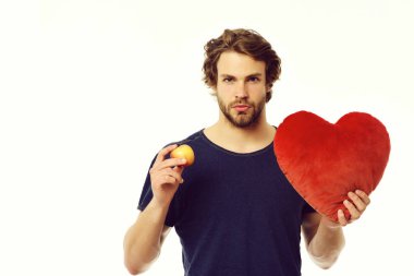 Elma tutan genç seksi maço ve büyük kırmızı oyuncak kalp.