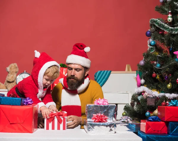 Χριστούγεννα οικογένεια ανοίγει δώρα σε σκούρο κόκκινο φόντο. — Φωτογραφία Αρχείου