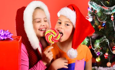 Kızlar lolipopu birlikte yer. Noel şapkalı kız kardeşler