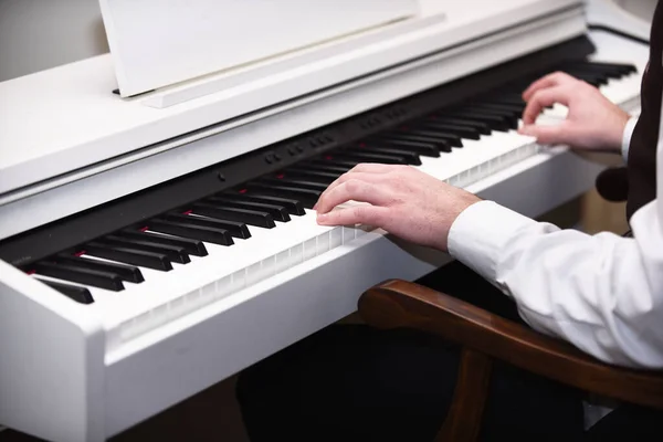 Mãos masculinas criando música no fundo do piano branco — Fotografia de Stock