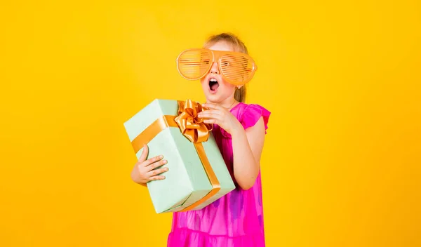 Dar zaskoczenia. czas na zakupy. Mała dziewczynka trzyma pudełko prezentów. Mały dzieciak z pudełkiem prezentów. Wszystkiego najlepszego. szczęście z dzieciństwa. Świętujmy wakacje. dziecko w letni dzień na żółtym tle — Zdjęcie stockowe
