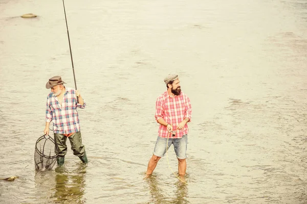 Equipo de pesca. Amistad masculina Padre e hijo pescando. Fin de semana. Pescador feliz con caña de pescar y red. Hobby y actividad deportiva. Pescando juntos. Los hombres están en el agua. Buen concepto de captura — Foto de Stock