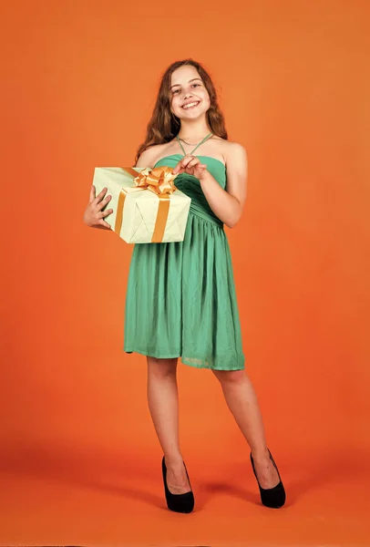 Pojďme slavit svátky. dítě v letním dni na oranžovém pozadí. je čas nakupovat. Holčička drží dárkovou krabici. Malý kluk s dárkovou krabicí. Všechno nejlepší. štěstí z dětství. Obchod s oblečením — Stock fotografie