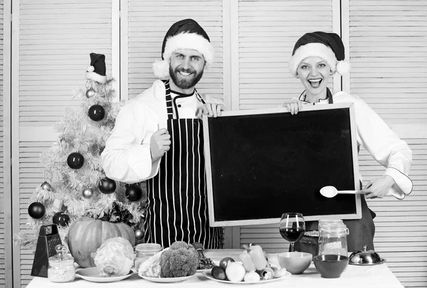 Man and woman chef santa hat near christmas tree hold blackboard copy space. Cooking christmas meal. Family traditional menu for christmas dinner. Menu for our family. Christmas recipe concept