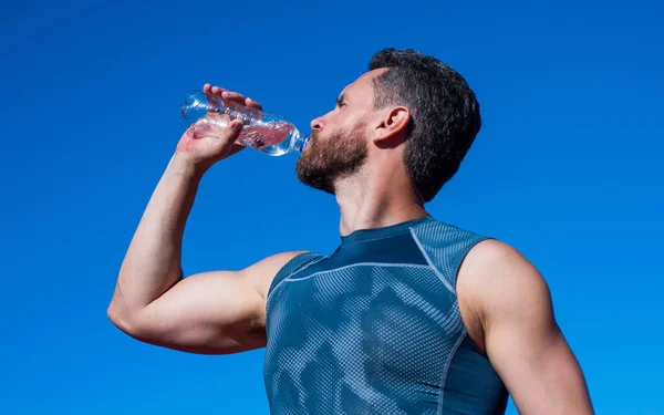 Adamın suya ihtiyacı var. Spor ve sağlıklı yaşam tarzı rutini. Vücuttaki su dengesi. Sporcu egzersizden sonra susar. Sporcu şişeden içiyor. Sağlık hizmeti. Kaslı adam spor üstüne su içiyor. — Stok fotoğraf