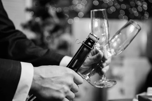Erkek eller, Noel süslemelerinde şampanya şişesini açıyor. Şampanya aç ve bayramı kutla. Yeni yılı şampanyalı içecekle kutlayın. Kadeh kaldırma ve tezahürat. Hadi kutlayalım. — Stok fotoğraf