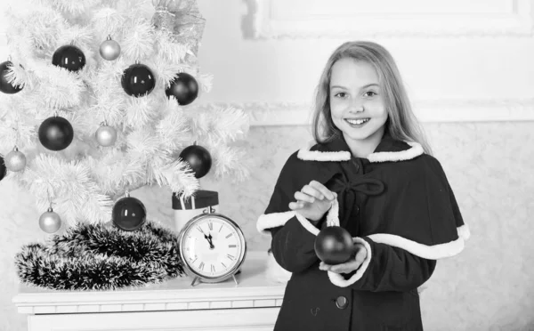 Świąteczny bal tradycyjny wystrój. Dzieci mogą rozjaśnić choinkę tworząc własne ozdoby. Najlepsze świąteczne dekoracje pomysłów na pokój dla dzieci. Dziecko czerwony kostium trzymać Boże Narodzenie ozdoba piłka — Zdjęcie stockowe