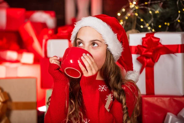 Gelukkige kindertijd concept. Ontdek de schoonheid van de winter. Gezellig en hygge. Warme chocolademelk. Cadeauwinkel. Kind kerstman hoed kerst geschenkdozen. Kind gelukkig meisje vinden geschenken in de buurt van kerstboom. Vrolijk kerstfeest. — Stockfoto