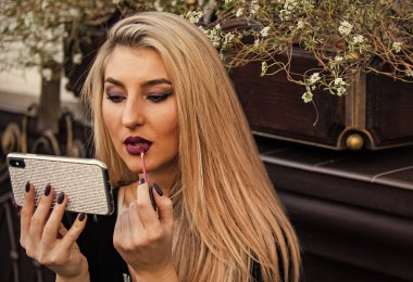 Modayı takip ediyorsun. Kozmetik ve makyaj malzemeleri. modamı takip et. Buluşmaya ya da buluşmaya hazırlan. Her zaman iyi görünüyorsun. Sarışın güzellik telefonu ayna olarak kullanıyor. Makyaj öğretmenliği moda blogu. Seksi bayan dudaklarına ruj sürdü.