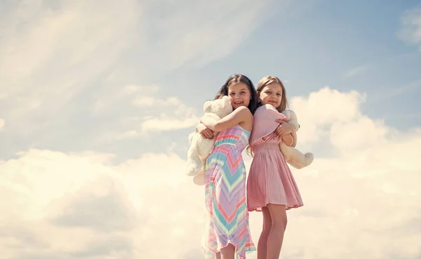 Best friends hold bear toy. two sisters with teddy bear. happy childhood. summer vacation. small girls embrace. love and support. concept of sisterhood and friendship. family bonding time. copy space — Stock Photo, Image
