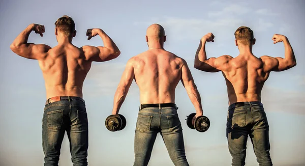 Culturistas atléticos. Concepto deportivo. Cuerpo muscular. Muscular significa poderoso. Más fuerza más músculo. El cuerpo utiliza proteínas para construir nuevos músculos. Hombres fuertes fondo cielo azul. Grupo hombres musculosos — Foto de Stock