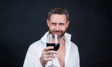 Düğmeleri iliklenmemiş seksi adam. Adam kırmızı şarap içiyor. Sevgililer Günü 'n kutlu olsun. Alkol içmek. Romantik bir randevuda yakışıklı bir erkek. Sevgilim olur musun? Şarap kadehli traşsız bir adam. Sommelier