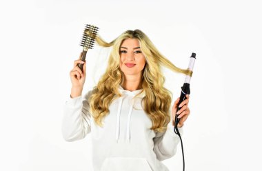 Farklı ambalaj teknikleri kullanarak. İhtiyaçlarınız için doğru saç maşasını seçin. Saç stili oluşturun. Uzun kıvırcık saçlı kadın saç maşası kullanıyor. Kuaför ipuçları. Sevimli sarışın kız. Çevrimiçi mağaza