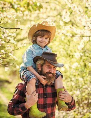 Babamı çok seviyorum. Baba ve çocuk bahar bahçesinde. Baba oğluna sırtında taşır. Sakallı adam baba küçük çocuğu sırtında taşıyor. Bahçe çiçeği. Babalar günün kutlu olsun. Aile tatili