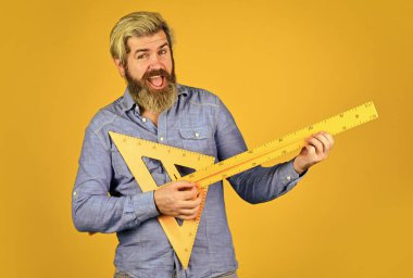 Bedava eğitim. Geometri öğretiyorum. Uzun ya da kısa. Sakallı adam cetvel kullanıyor. Eğitim konsepti. Okul dersleri. Eğlenerek ders çalışmak. Ölçüm aracı. Öğretmen sapı. Santimetre ölçüyorum. Okul eğitimi