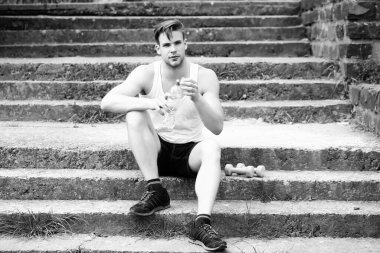 Ciddi yüzlü sporcu beton merdivenlerde oturuyor.