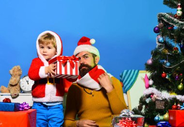 Noel Baba ve küçük yardımcısı Noel ağacının yanındaki hediye kutularının arasında.