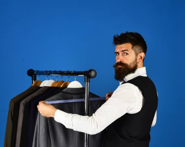 Elbise rafında sakallı bir adam. Tasarımcı önlem alır