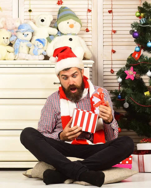 Man with beard opens present. Guy in hat and scarf — Stock Photo, Image