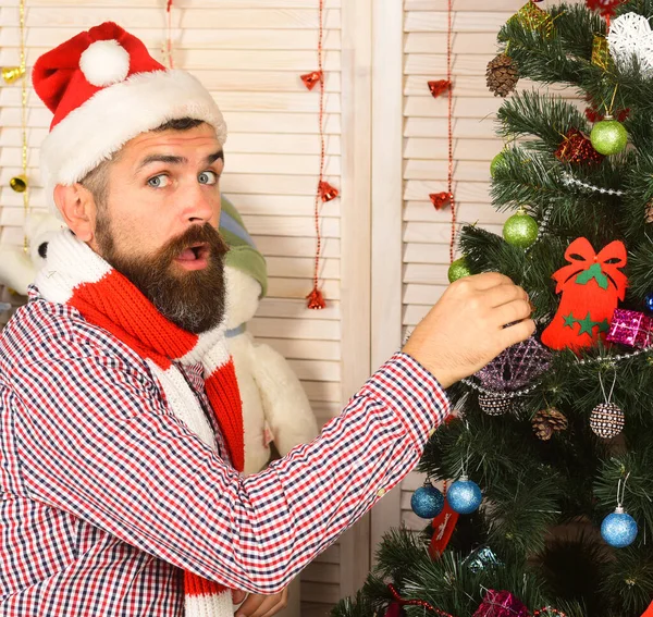 Guy in hat and scarf stands by fir tree — Stock Photo, Image