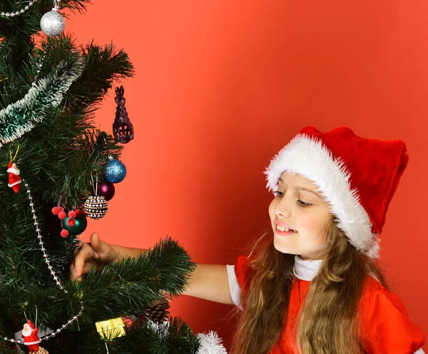 Дівчина з довгим волоссям в різдвяній шапці прикрашає дерево — стокове фото
