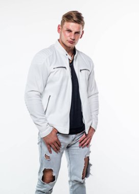 Sokak tarzı pozlar veren seksi genç adam beyaz, moda modasına uygun giyiniyor.