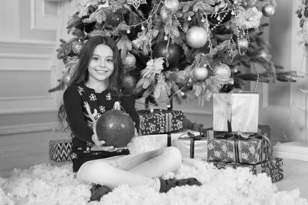 Noel süslemeleri. Mükemmel kış tatilim. Noel ağacının yanındaki küçük kız. Çocuk Noel 'i evde kutluyor. Kış gelenekleri. Hediyelik eşya dükkanı konsepti. Sevimli çocuk Noel süveteri giyiyor. — Stok fotoğraf