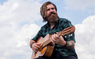 Pop müzik. müzik teli enstrümanı. Olgun karizmatik erkek gitarist. Sakallı ve bıyıklı adam gitar çalıyor. Kareli gömlekli sakallı adam şarkı söylüyor. Müzisyen