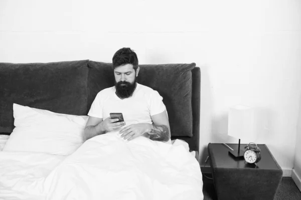 Vado online. L'uomo barbuto usa smartphone a letto. Tecnologia per la casa. Adozione della tecnologia mobile. Tecnologia a banda larga. Nuove tecnologie. La vita moderna. Connessione internet a casa — Foto Stock