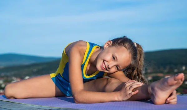Happy kid in sport training clothes workout outdoor, stretching — Stock Photo, Image