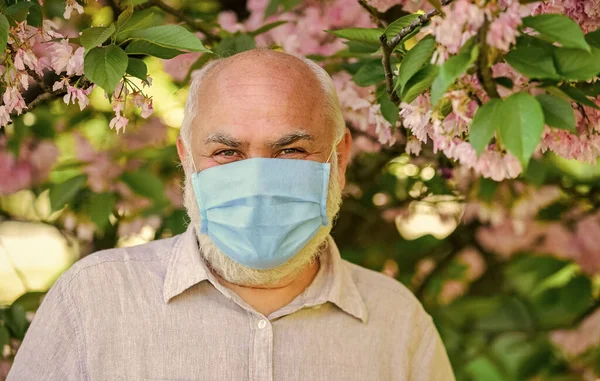 Umulig å lukte. bruke maske i blomstrende rosa sakurapark. Ta vare på helsen din. mann med beskyttende maske. Det lukter blomst på Coronavirus karantene. observere forsiktighetsregler ved pandemi. sunt liv – stockfoto