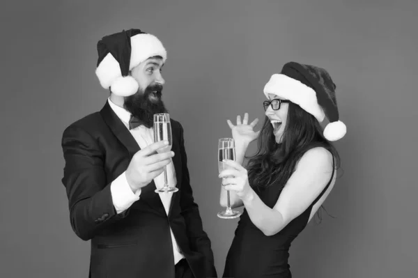 Vánoční zábava. slavnostní párová hostina. Muž ve smokingu se ženou v Santově klobouku. Veselé Vánoce. obchodní pár pije šampaňské. Vánoční večírek. milují nový rok. koncepce pozdravů — Stock fotografie